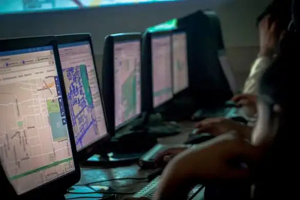 people at a mapping event in front of a row of computer screens showing different views of the OSM.org homepage