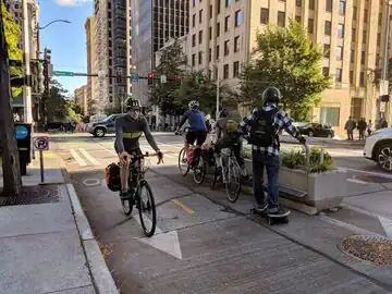 Foot- and handrests on a planter (bi-directional cycleway). highway=cyclist_waiting_aid direction=backward footrest=yes handrest=yes side=right count=3 (Assuming the way is directed like the arrow on the cycleway, the device is used in backward direction and is located on the left side of the OSM way, but it's located on the right side=* for the users.)
