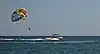Motorboat towing a parasailing parachute canopy in the air, in Rhodes, Greece