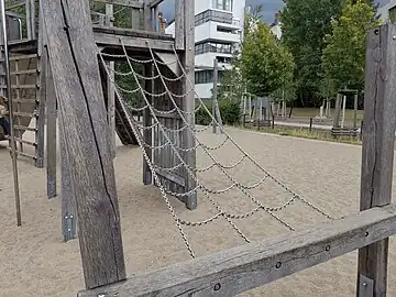 A climbingframe made from material=chain leading up to a platform that is part of a structure.