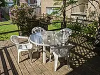 Porch in city residential neighborhood block area with plastic chairs and glass table